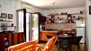 A kitchen with wooden cabinets, a dining table with chairs, a refrigerator, and a hanging light fixture. - Apartment Ela (Solta)