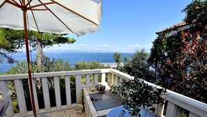 A balcony with a white railing, a table, and a potted plant. - Apartment Ela (Solta)
