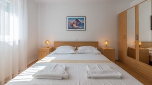 Ein Hotelzimmer mit einem Bett, zwei Nachttischen mit Lampen, einem großen Spiegel und einem Bild an der Wand.
