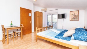 Ein Zimmer mit einem Bett, einem Schreibtisch mit Stühlen, einem Fernseher und einem Fenster.