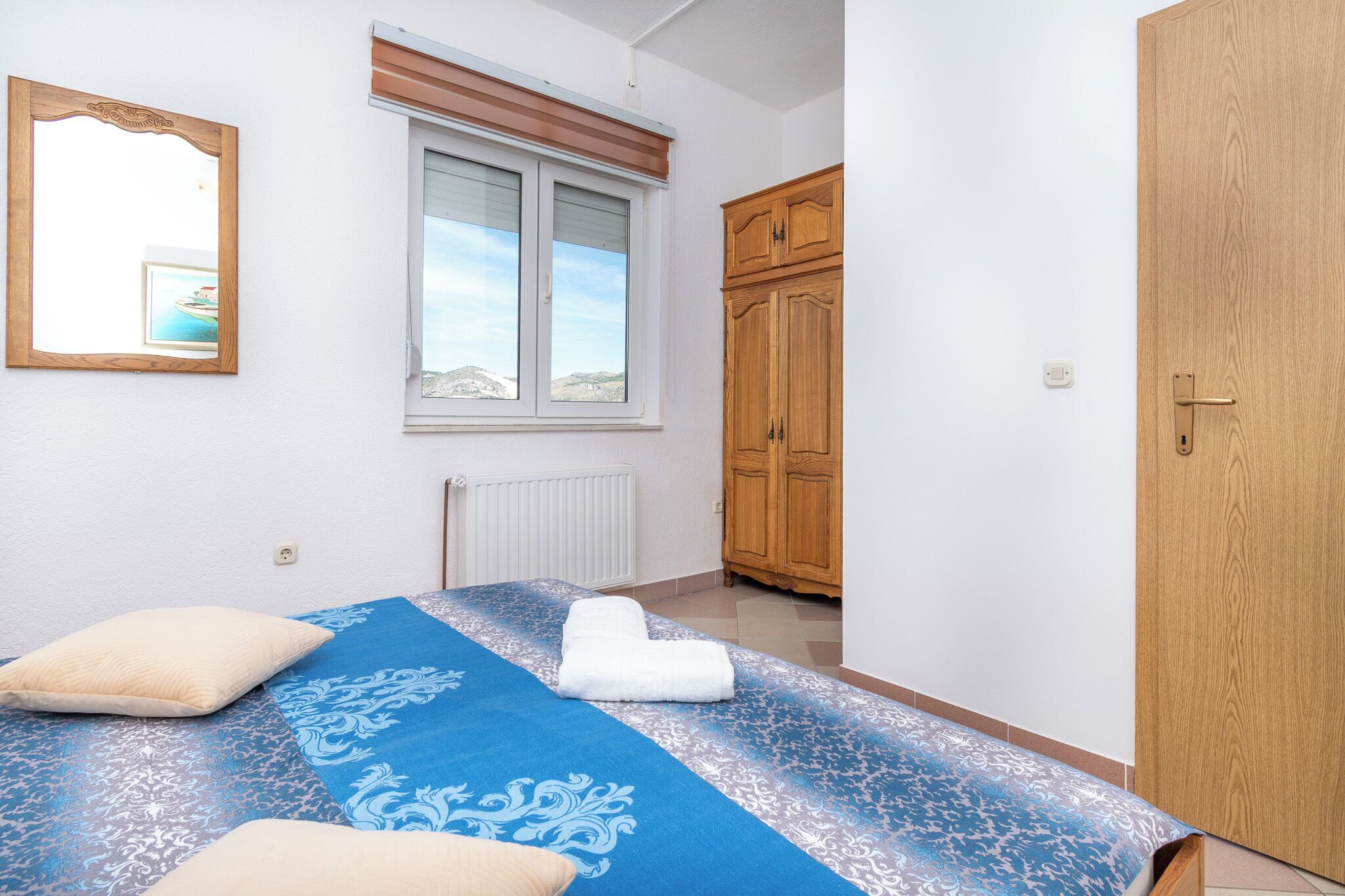 Una camera da letto con un letto, una finestra, un armadio in legno e una porta.