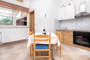 Une cuisine avec une table à manger, des chaises, une bouteille de champagne et une vue sur l’extérieur.