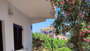 A patio with a table and chairs, a potted plant, and a building in the background. - Apartment Slaven (Marina)