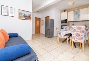 A compact living space with a kitchenette, a dining area, and a sofa with cushions. - Apartment Slaven (Marina)