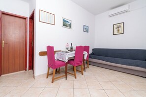 A dining area with a table set for four, a sofa, and a door. - Apartment Slaven (Marina)