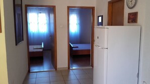 A hallway with two bedrooms, each with a bed and a window. There is a refrigerator in the room. - Apartment Slaven (Marina)