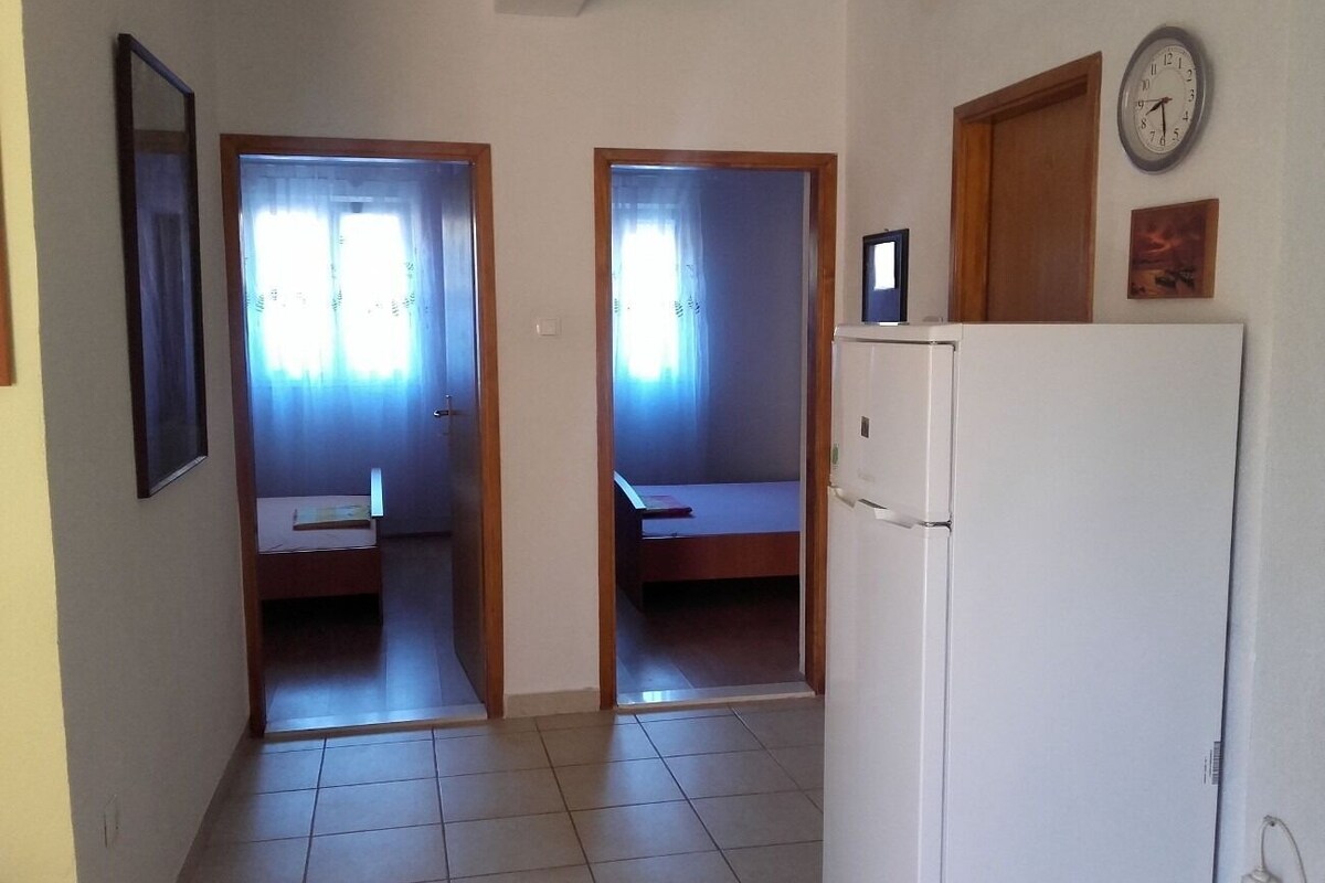 Ein Flur mit zwei Schlafzimmern, jedes mit einem Bett und einem Fenster. Im Zimmer befindet sich ein Kühlschrank.
