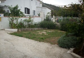 A white house with a garden, a gravel driveway, and a metal fence. - Apartment Slaven (Marina)