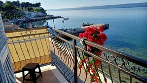 Ein Balkon mit Stuhl, Geländer und Blick aufs Meer.