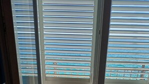 Ein Zimmer mit einer Schiebeglasdoor zur einem Balkon mit horizontalen Jalousien.
