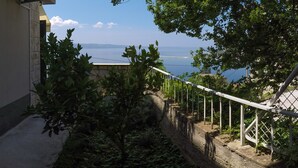 A balcony with a view of the sea, a stone wall, and a metal railing. - Apartment Iva (Omis)