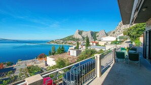 A balcony with a view of a coastal town, a mountain, and the sea. - Apartment Iva (Omis)