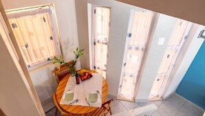 A dining area with a round table, chairs, a vase with flowers, and a fruit bowl. - Apartments Zeljko (Korčula)