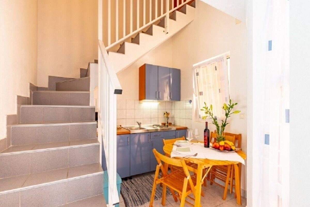 A staircase leading to a kitchen with a dining area.