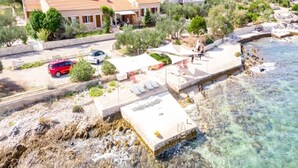 A coastal property with a swimming pool, lounge chairs, and a rocky shoreline. - Apartments Zeljko (Korčula)