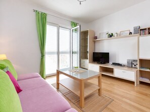 Ein modernes Wohnzimmer mit einer Couch, einem Fernseher, einem Schreibtisch und einem Bücherregal.