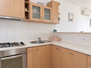 A kitchen with wooden cabinets, a stainless steel sink, and a gas stove. - Apartment Ljilja (Hvar)
