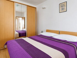 Ein Schlafzimmer mit Bett, Kleiderschrank, Spiegel und einem Bild an der Wand.