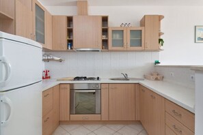 A modern kitchen with wooden cabinets, a gas stove, an oven, and a sink. - Apartment Ljilja (Hvar)
