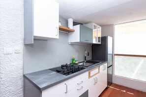 Uma cozinha compacta com fogão a gás, pia e armários brancos.