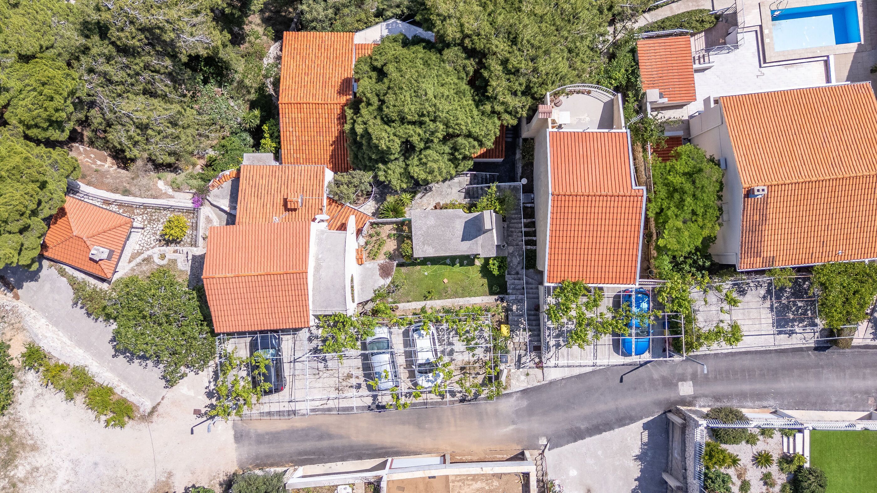An aerial view of a residential area with multiple buildings, a swimming pool, and a parking area.