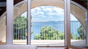 A bedroom with a large window, a bed, and a view of the sea. - Apartments Marko (Omis)
