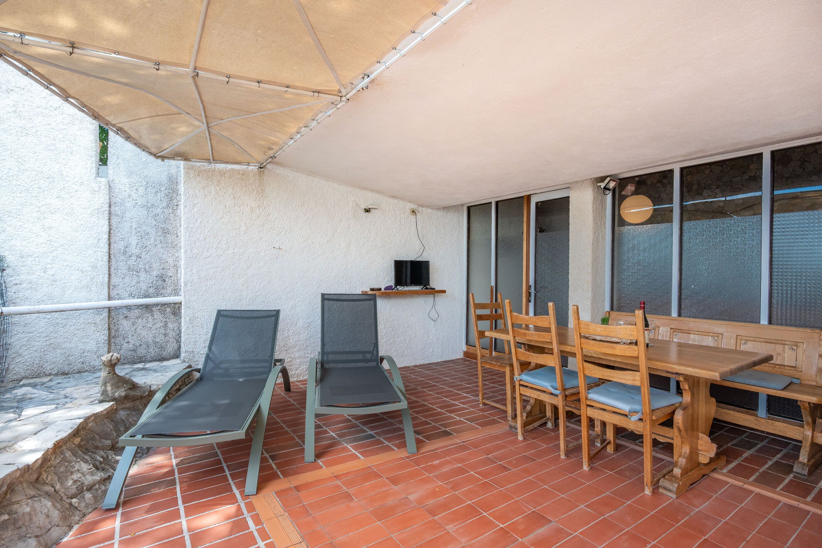 A patio with a table and chairs, a TV, and a stone wall.