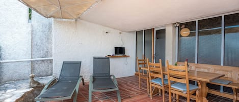 A patio with a table and chairs, a TV, and a stone wall.