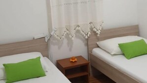 Una stanza con due letti, ognuno con un cuscino, un tavolino e una sedia.