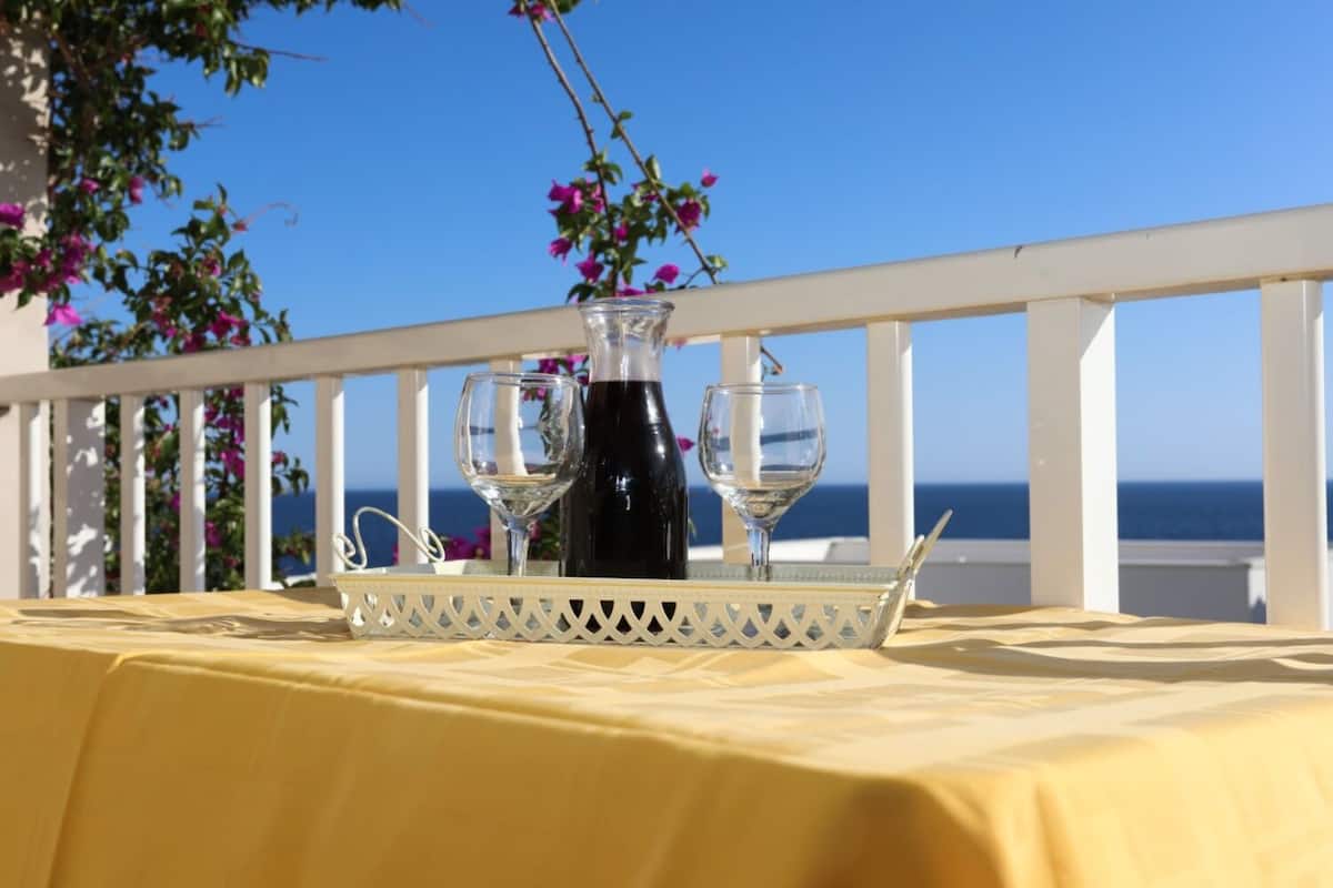A table with a yellow tablecloth, two wine glasses, and a bottle on a white tray.