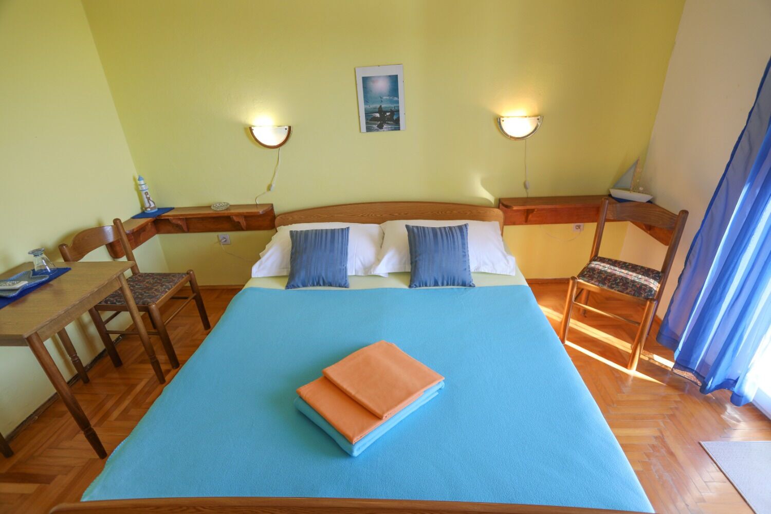 Una habitación con una cama, dos mesitas de noche, un escritorio y sillas.