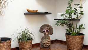 A corner with three potted plants, a wooden sculpture, and a shelf with a bowl. - Apartments Dijana (Blato)