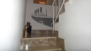 Una escalera con detalles de mármol y un mural de un barco en la pared.