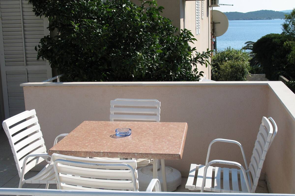 Une petite terrasse extérieure avec une table et quatre chaises blanches.