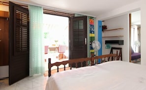 A bedroom with a bed, a fan, and a view of the outside.