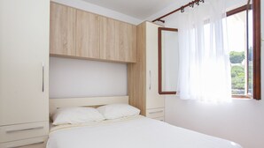 Una camera da letto con un letto, un armadio e una finestra con tende.