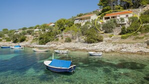 Una zona costiera con acque limpide, diverse imbarcazioni e edifici su una collina.