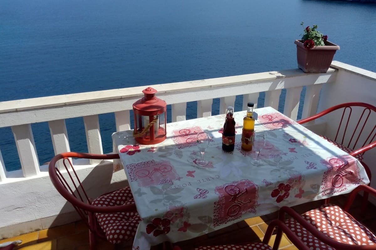 A table set with two bottles and a lantern on a balcony overlooking a body of water.