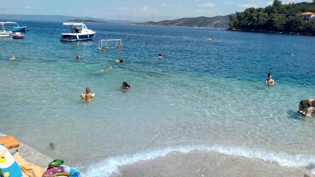 A beach with clear water, people swimming, and boats. - Apartments Ivo (Korčula)