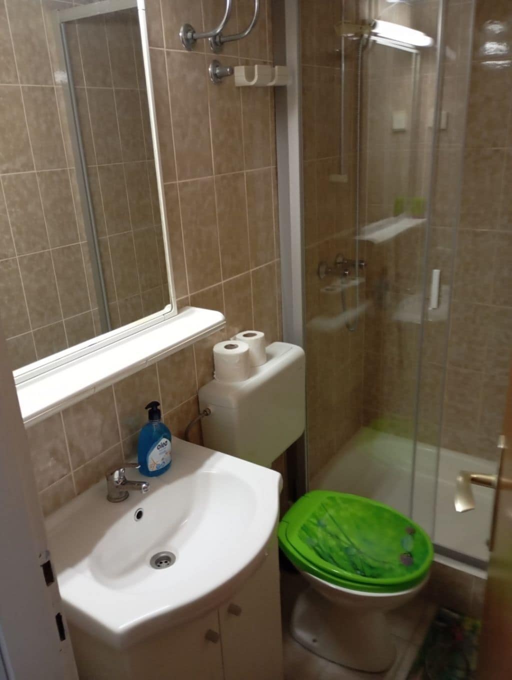 Ein Badezimmer mit Waschbecken, Spiegel, Toilette und Dusche.