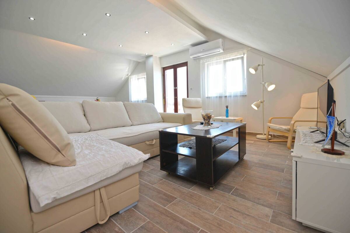 A modern living room with a beige sofa, a black coffee table, and a white cabinet.