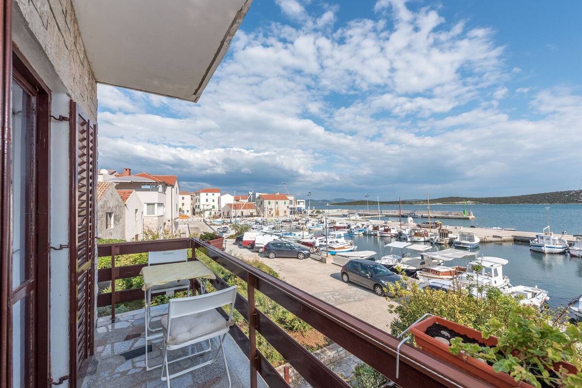 A balcony with a view of a marina, boats, and buildings.