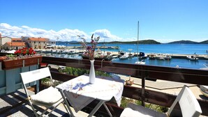 A terrace with a table and chairs overlooking a marina with boats and a clear blue sky. - Apartment Mili Sea View Betina (Tisno)