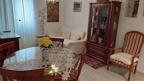 Et spiseområde med et glasbord, stole, et skab og en sofa.