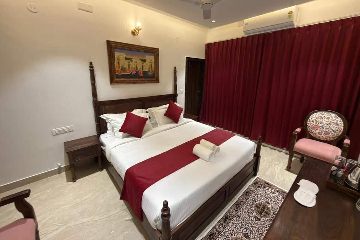 A hotel room with a large bed, a wooden nightstand, a chair, and a painting on the wall.