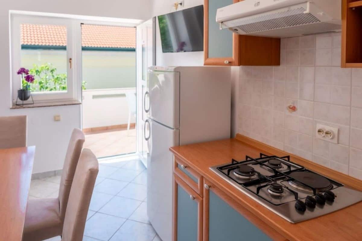 Egy konyha gáztűzhellyel, hűtőszekrénnyel és egy televízióval, amelyet a tűzhely fölé szereltek.