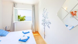 A hotel room with a bed, a window with curtains, a wall-mounted mirror, and a tree decal. - House Ned (Tucepi)