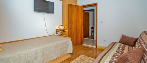 Quarto com cama, sofá, televisão e armário de madeira.