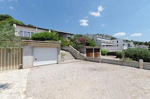 A residential area with houses, a garage, and a gravel driveway. - Apartments Ema (Murter-Kornati)