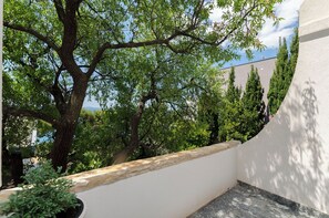 Un balcon donnant sur des arbres et un immeuble.